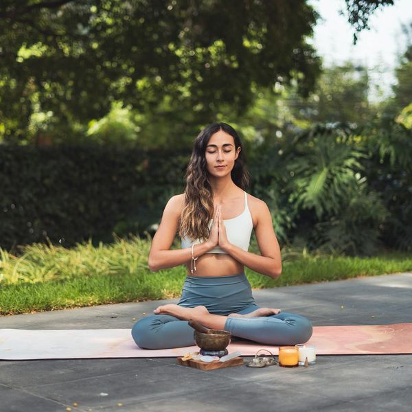 Person meditating peacefully on a yoga mat in a natural setting.